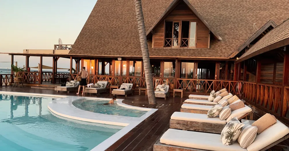 Charming boutique hotel pool area surrounded by tropical plants at sunset